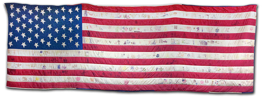 Photograph of the American flag quilt that hangs on the wall in our library. The quilt was hand-decorated by students and staff. 
